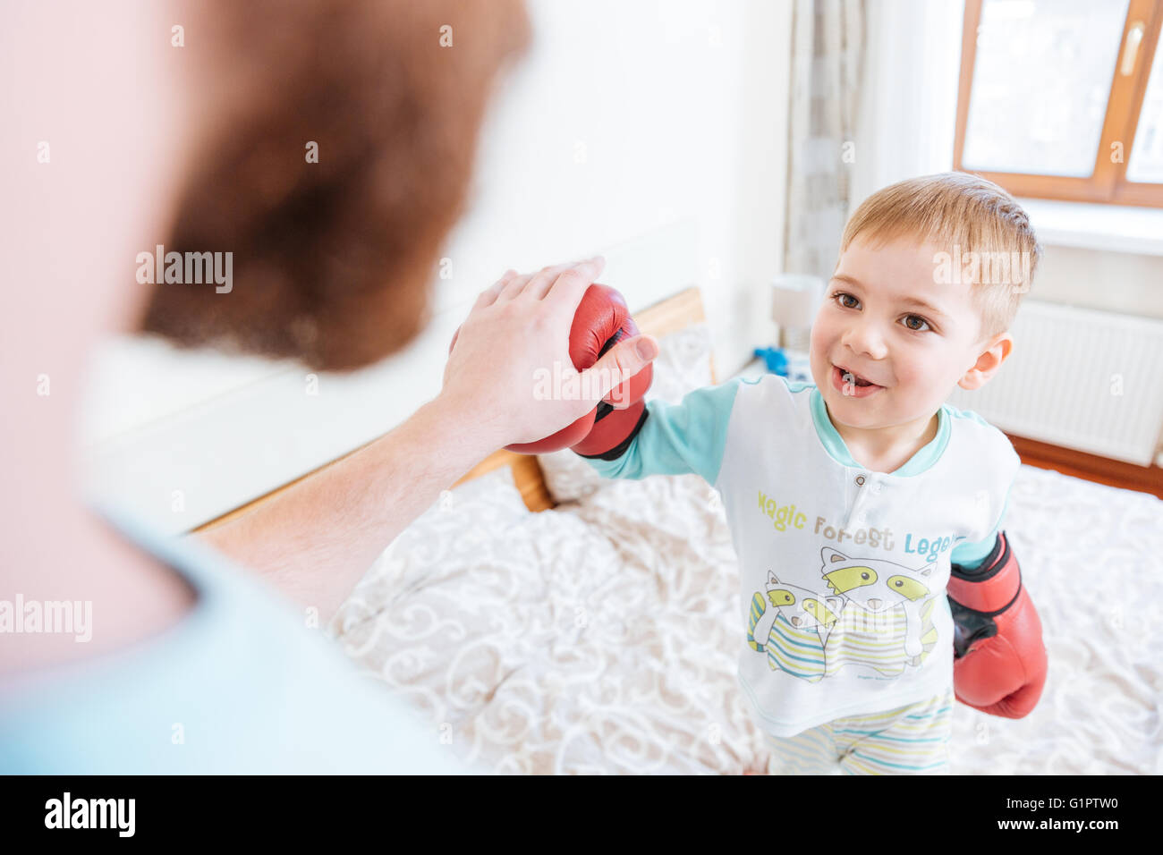 Happy little boy playing with his father using boxing gloves Stock Photo