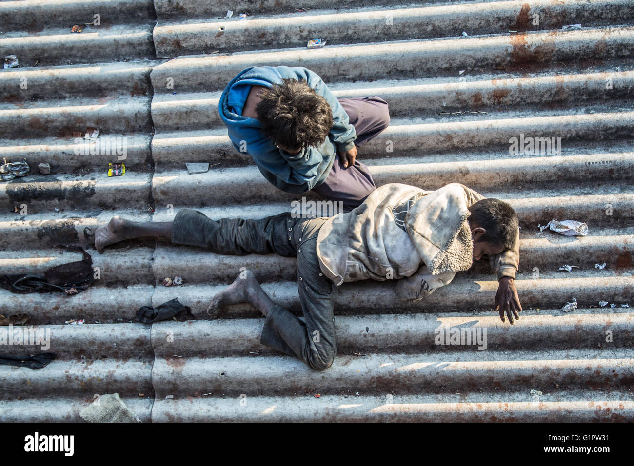 An image taken, at morning, down on two homeless children sleeping on a roof near a train station in Janwar, India. Stock Photo