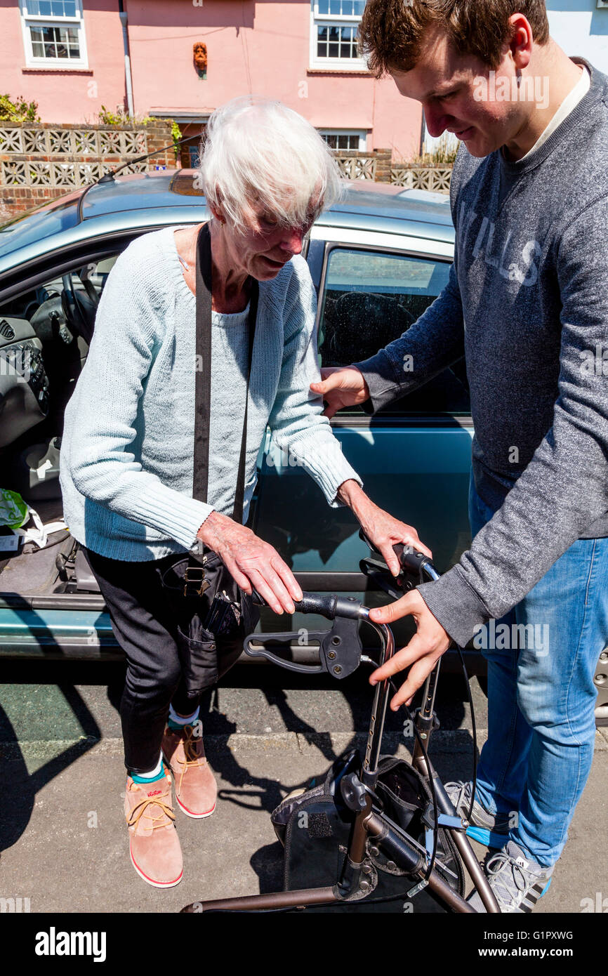 An Elderly Disabled Woman Getting Out Of A Car Helped By Her Grandson, Brighton, Sussex, UK Stock Photo