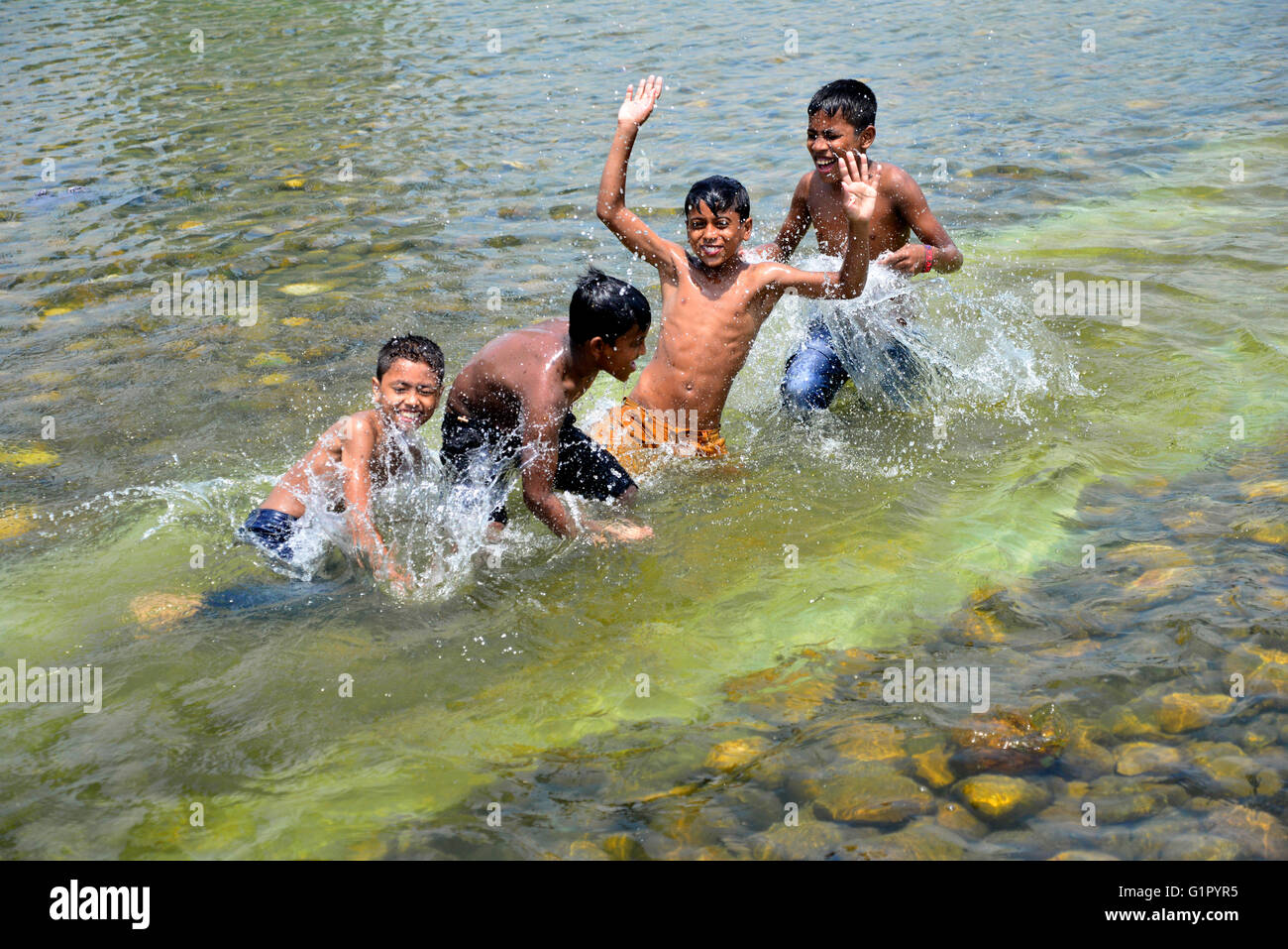 Bangladeshi children bathe in a Sohrawardi Uddan Lake during a hot