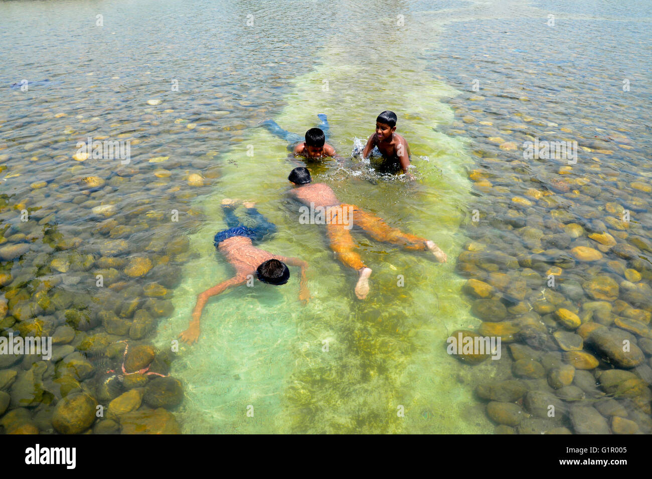 Bangladeshi children bathe in a Sohrawardi Uddan Lake during a hot