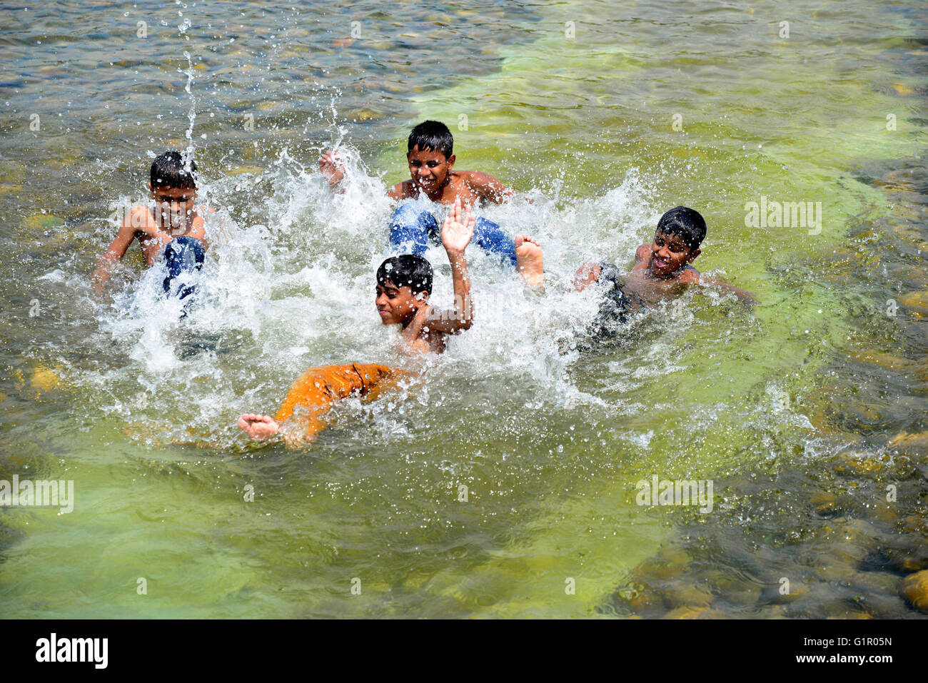 Bangladeshi children bathe in a Sohrawardi Uddan Lake during a hot