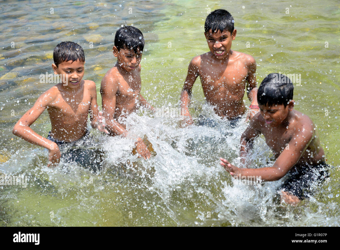 Bangladeshi children bathe in a Sohrawardi Uddan Lake during a hot