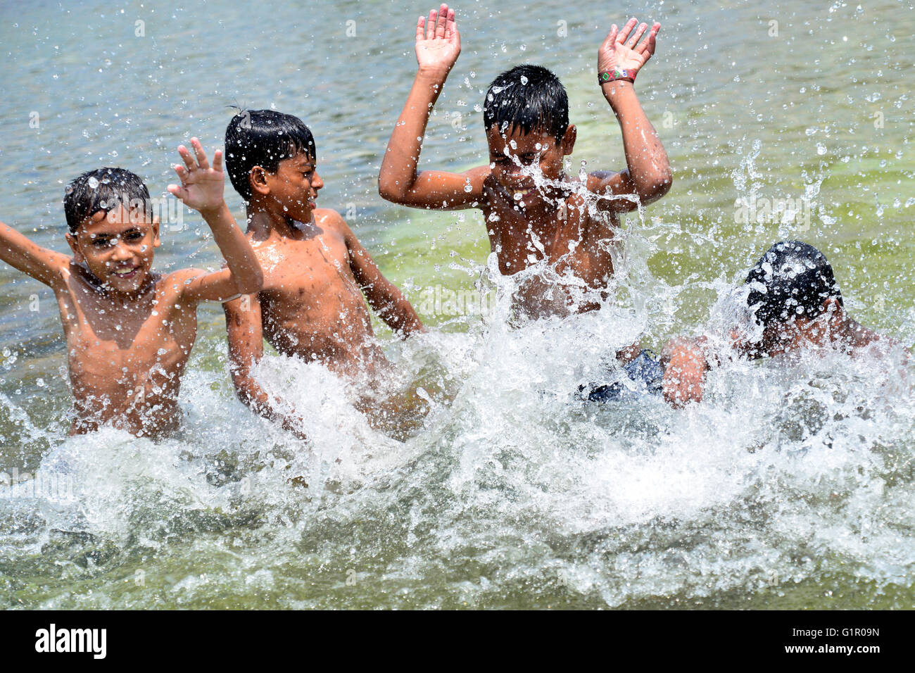 Bangladeshi children bathe in a Sohrawardi Uddan Lake during a hot