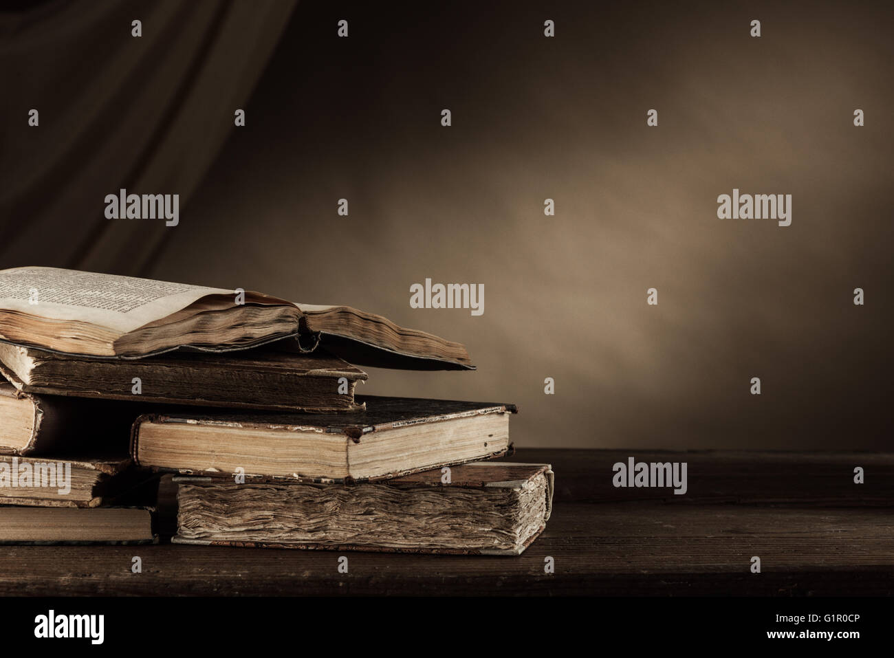 Ancient books on a wooden table and drape on background, literacy and knowledge concept Stock Photo