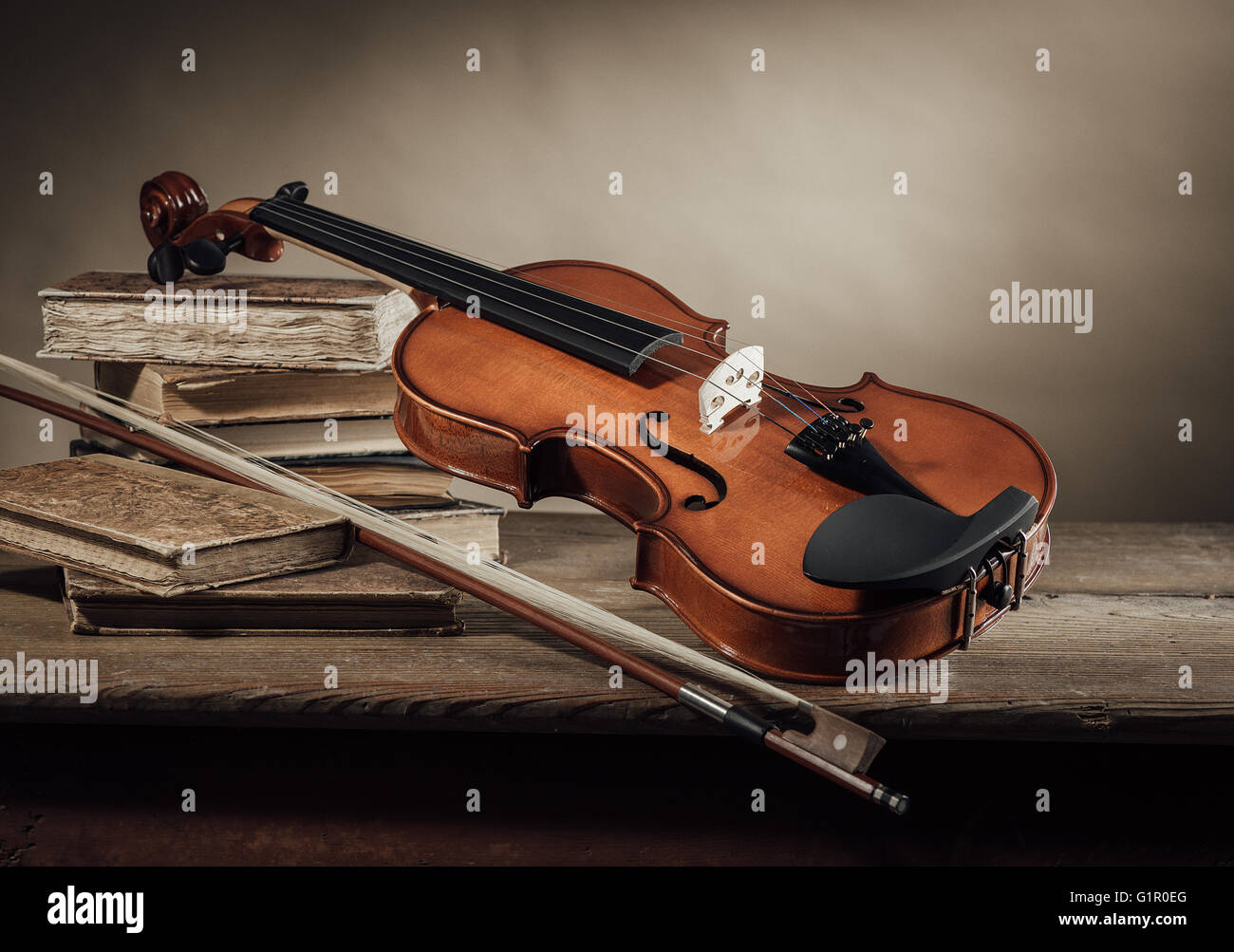 Old violin, bow and books on a rustic wooden table, still life Stock Photo