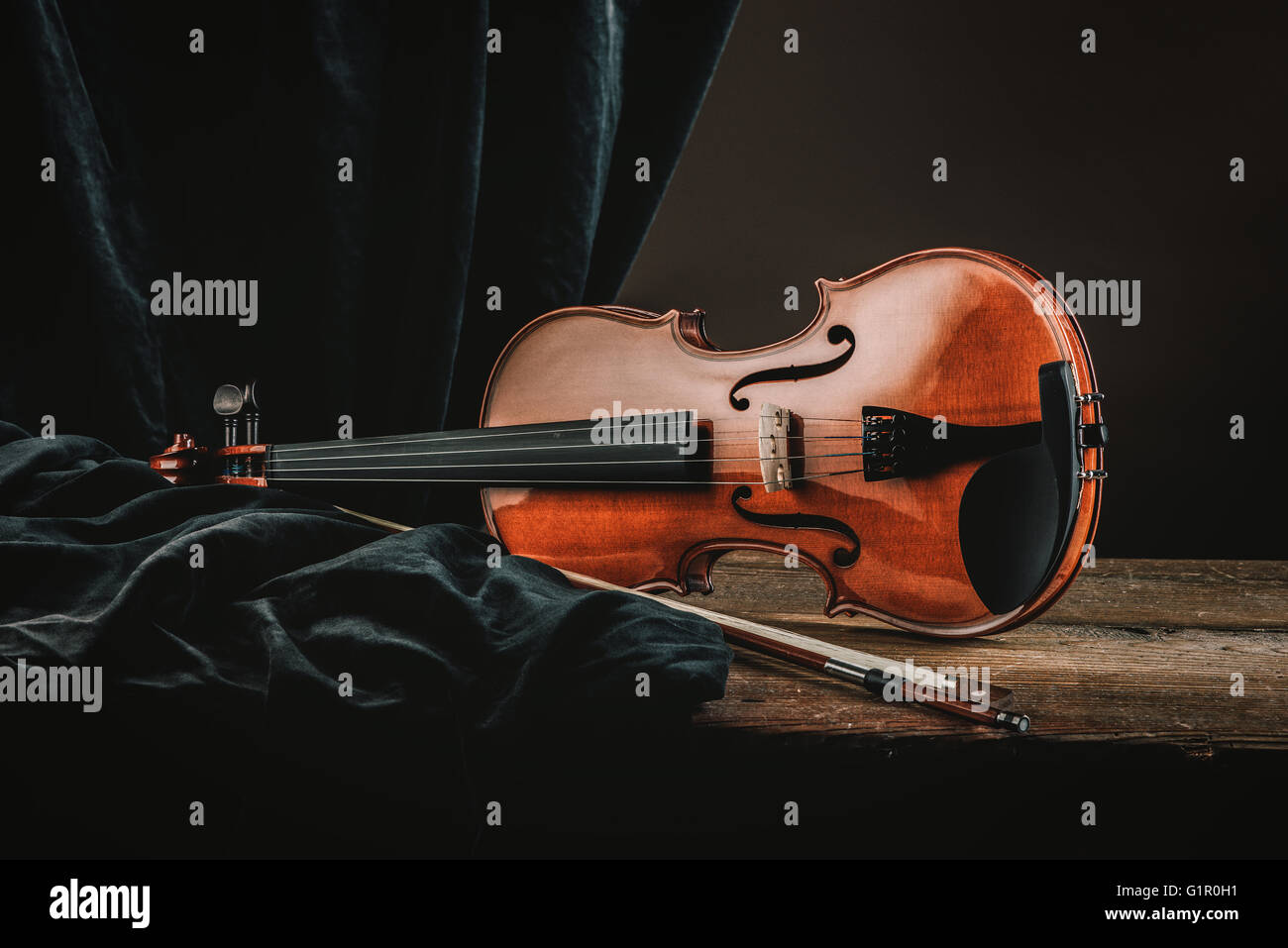 Old violin on a rustic wooden table with bow and drape still life, arts ...