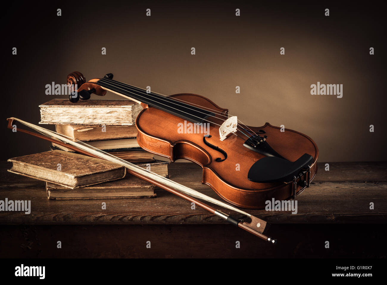Violin, bow and old books on a rustic wooden table, arts and music concept Stock Photo