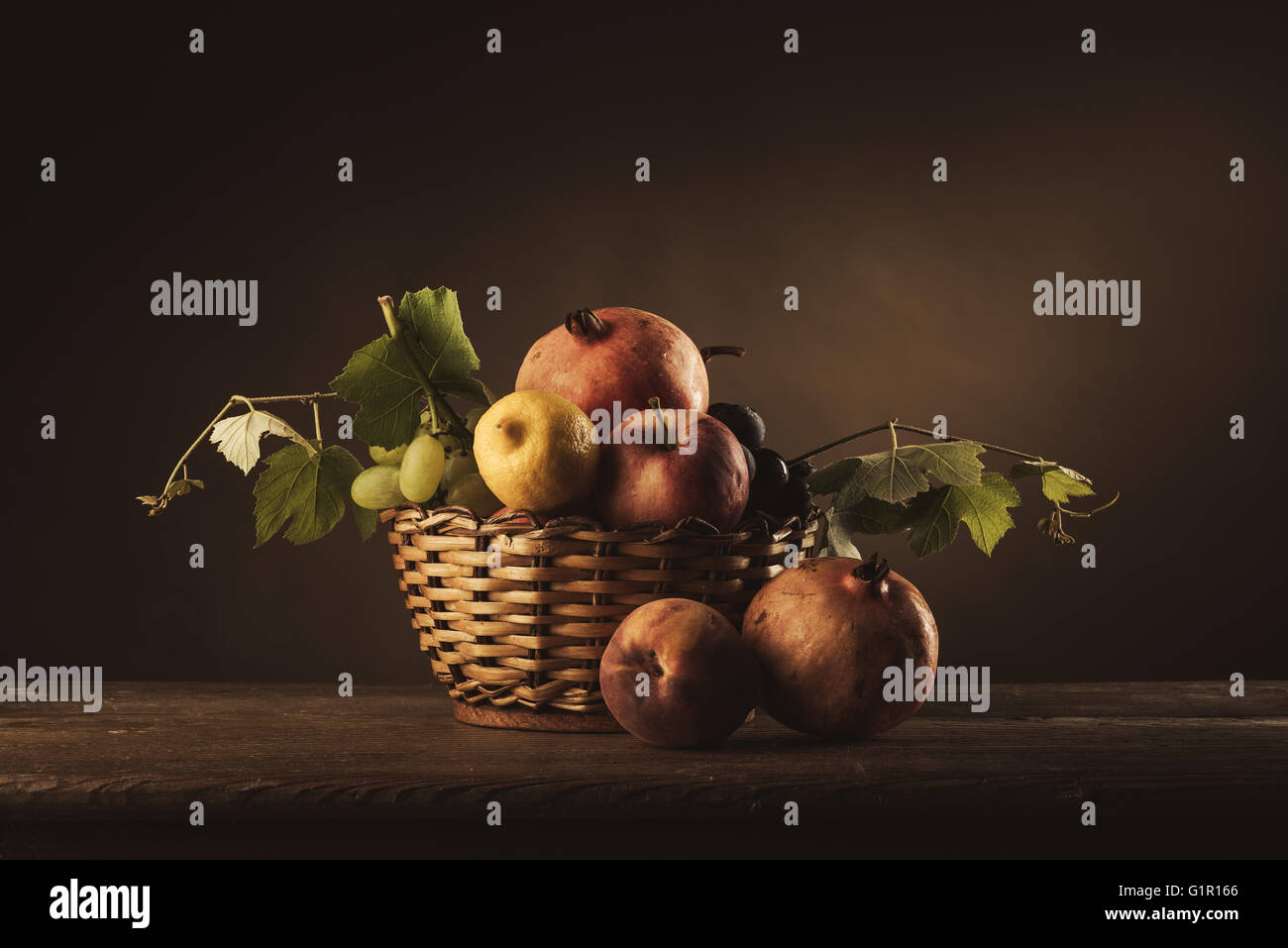Seasonal ripe fruit in a basket on a rustic wooden table and vine ...