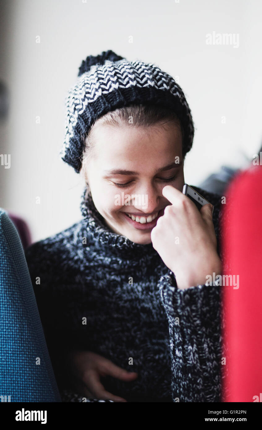 A girl in winter clothes looking down and smiling Stock Photo