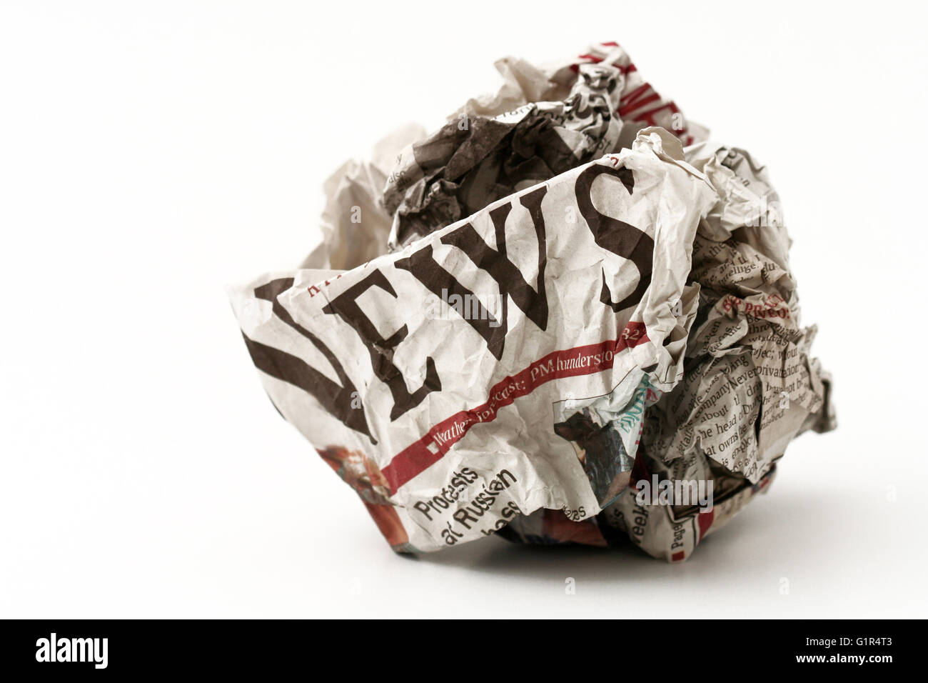 Horizontal front view of a ball of twisted newspaper page with the word news visible isolated on white background Stock Photo