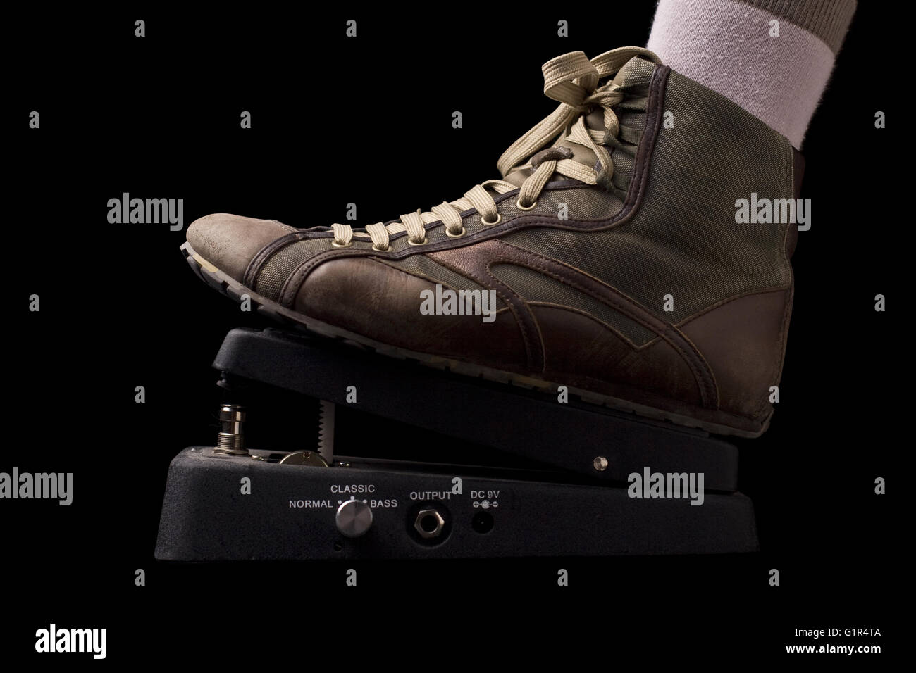 Horizontal side view of a show pressing a rock music pedal on black ...