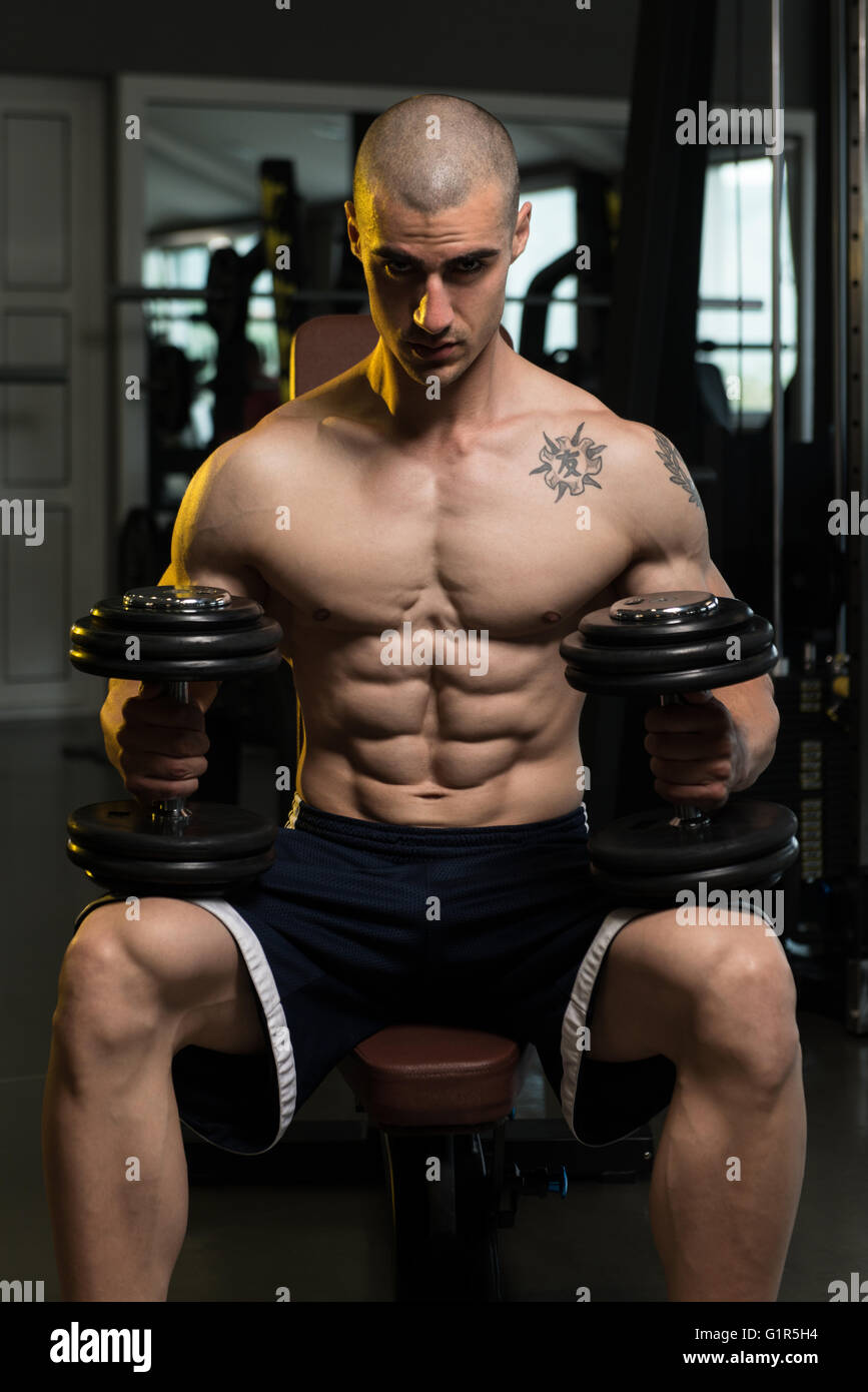 Portrait Of A Physically Fit Young Man In A Healthy Club With Dumbbells Stock Photo