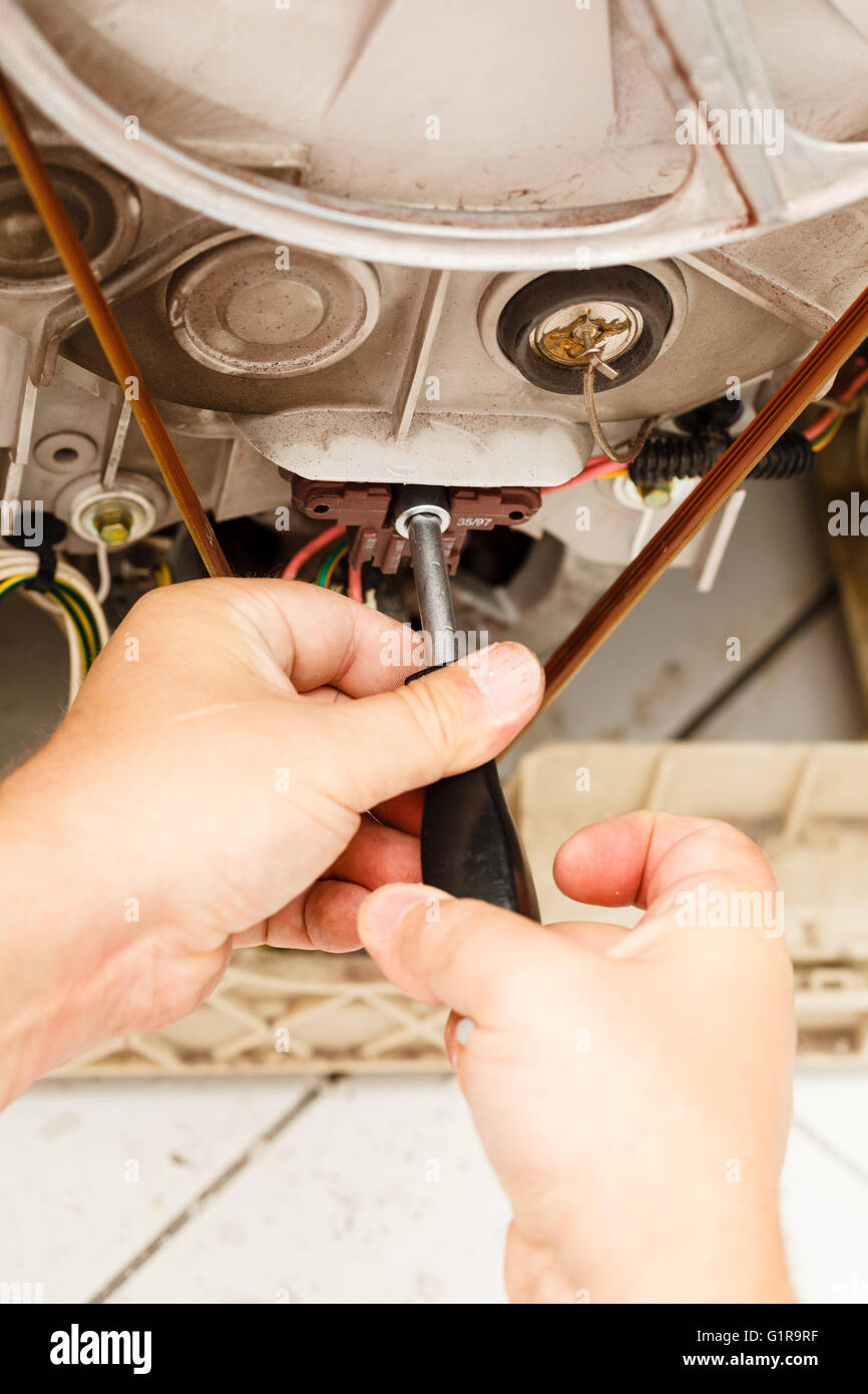 Mechanical engineering industry repair concept. Person fixing washing machine. Broken laundromat