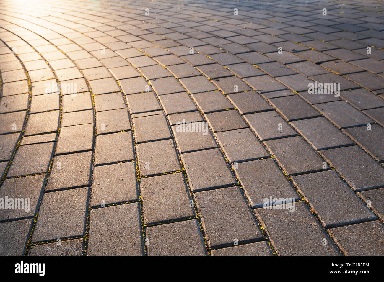 Turning walking lane in the evening sunlight, cobblestone pavement, abstract urban road background photo with selective focus on Stock Photo