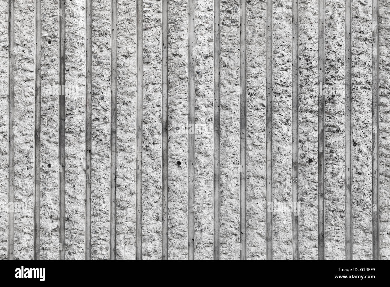 Rough gray concrete wall with vertical relief lines, frontal background