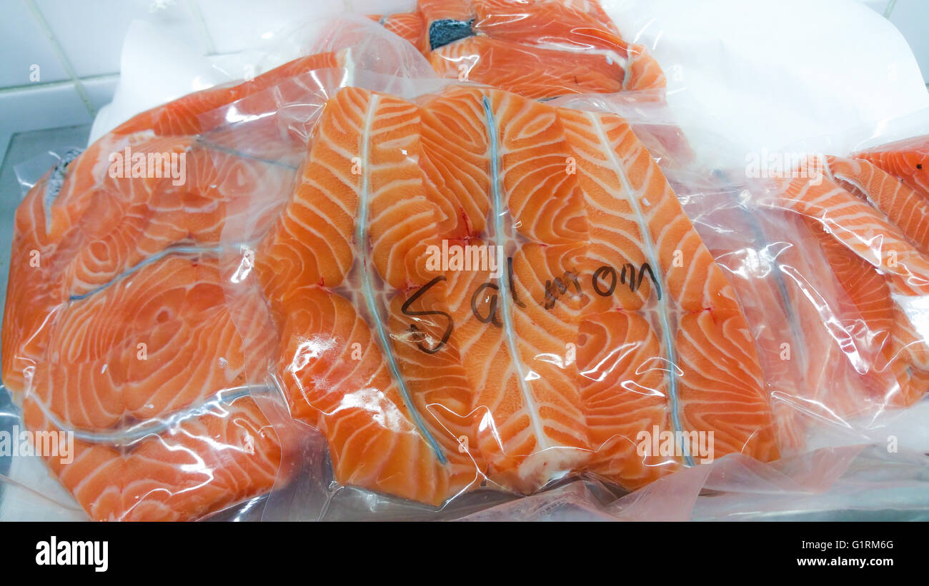 Pile of vacuum packed grilled salmon medallions, at a fish market Stock
