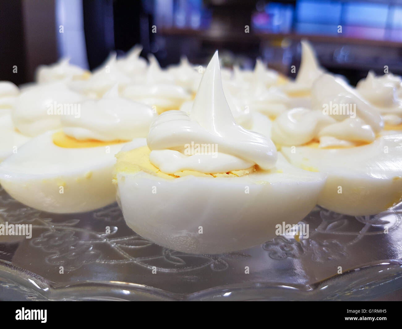 Closeup on hard boiled eggs and squeezed mayonnaise, on a glass plate