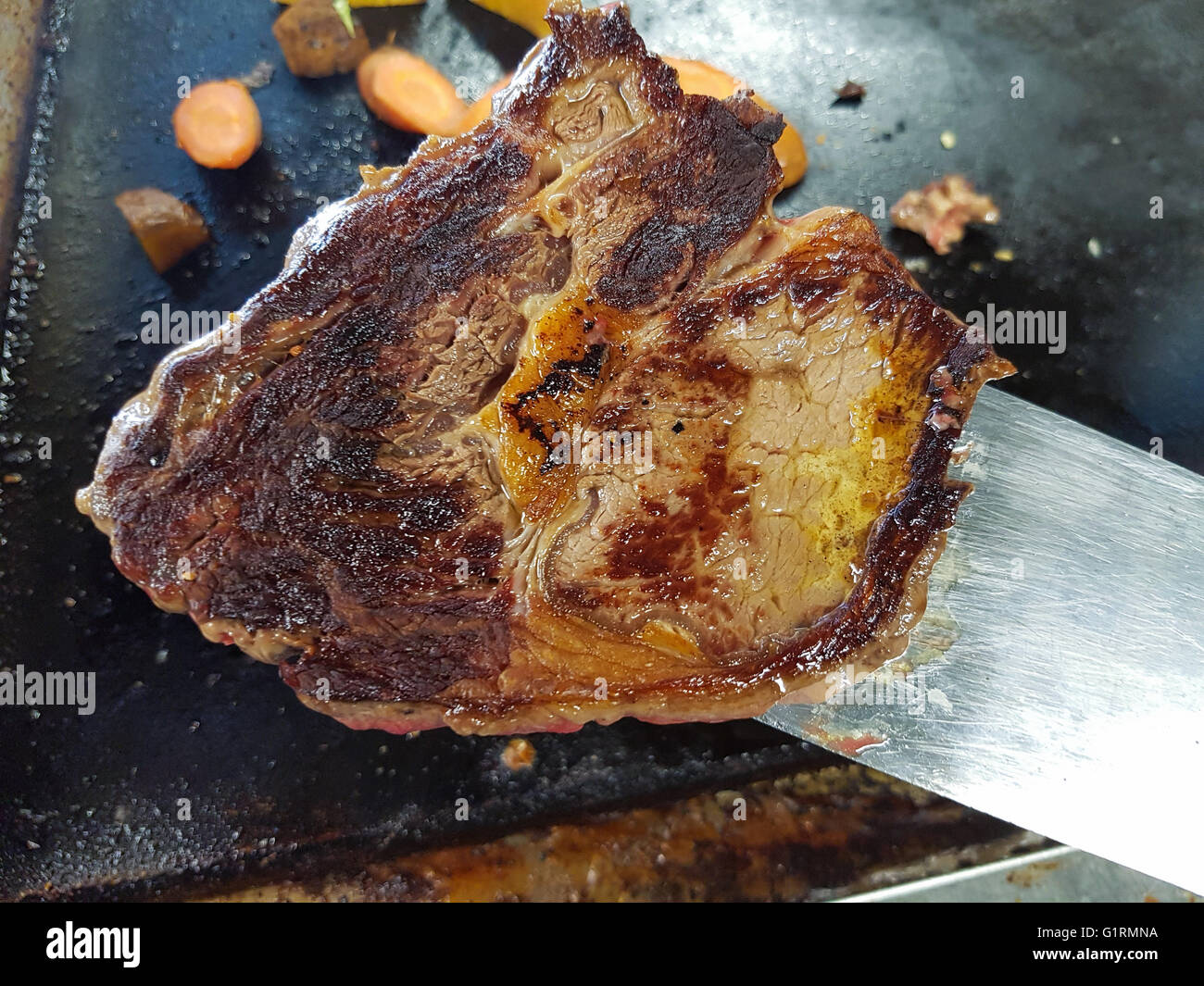 Fried black angus entrecote steak, on a spatula, infront of a frying table Stock Photo