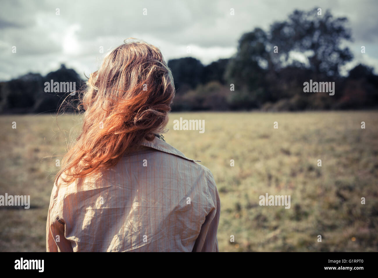 A young woman is standing in a field Stock Photo - Alamy