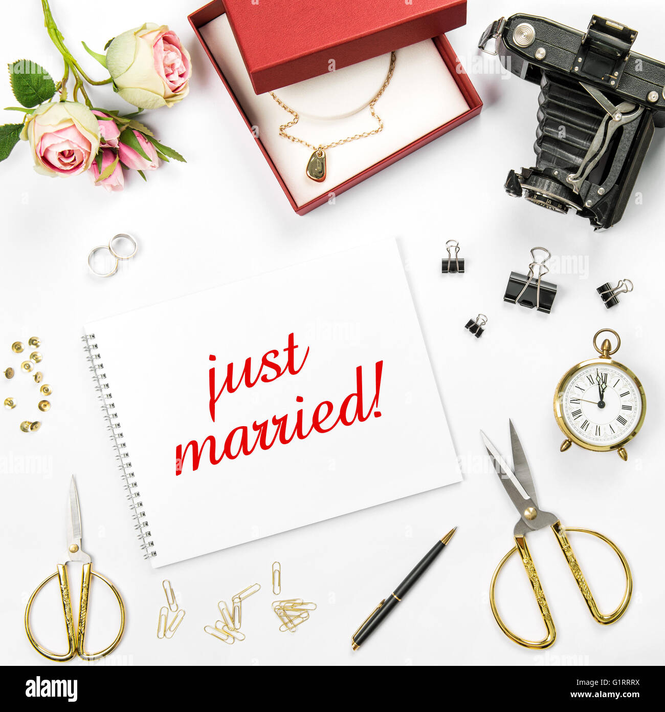Wedding flat lay background with gift box, golden rings and rose flowers. Sample text just married Stock Photo