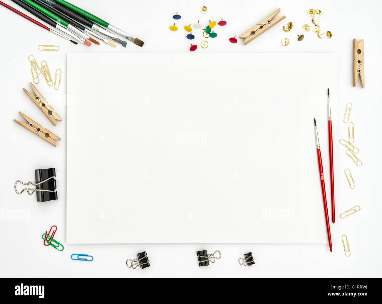 Flat lay with sketchbook, brushes, paper, office supplies on white background. Top view Stock Photo