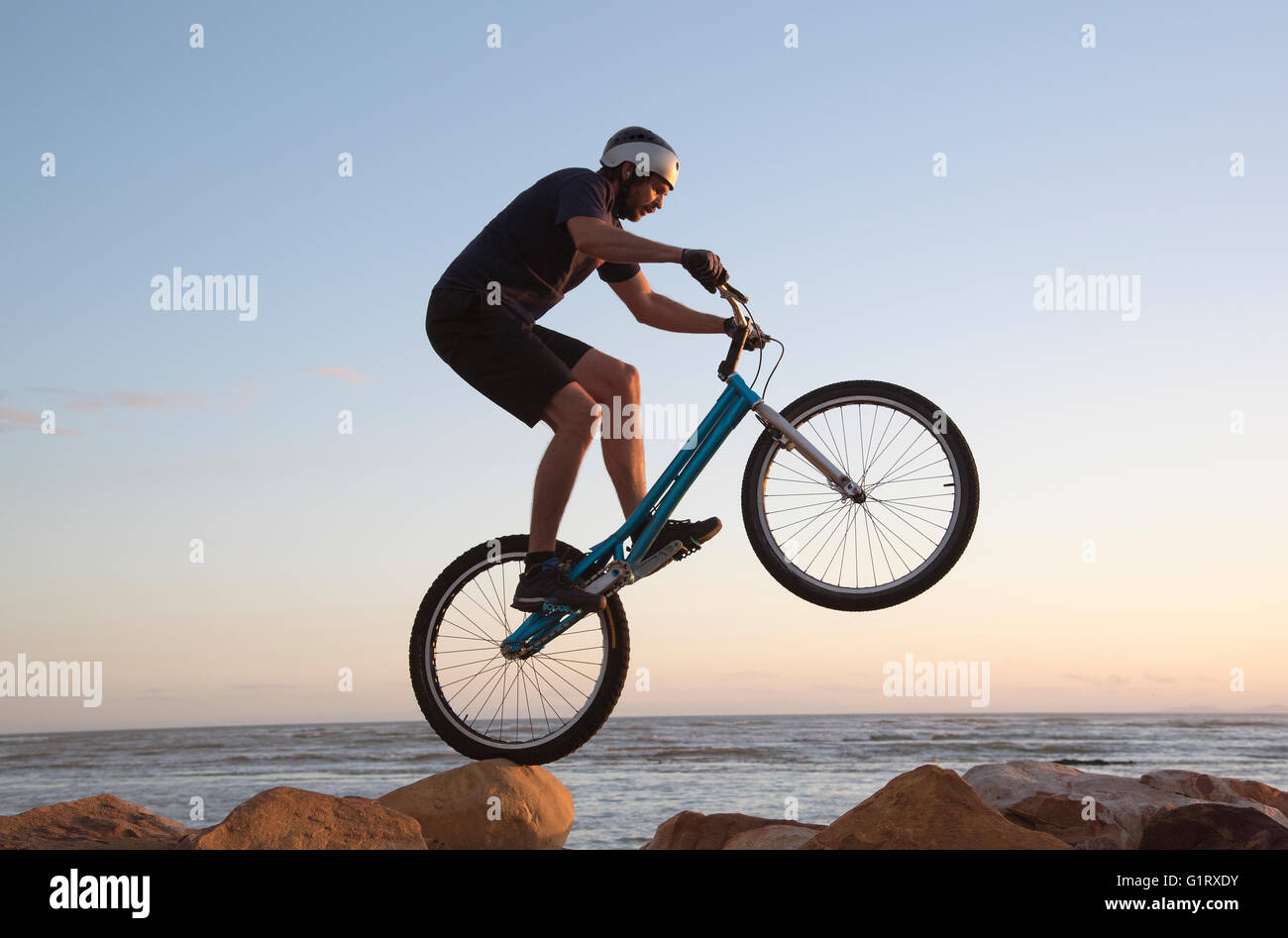 THE STRAND WESTERN CAPE SOUTH AFRICA. A mountain bike rider skillfully  riding over rocks on the shoreline at The Strand beach Stock Photo - Alamy