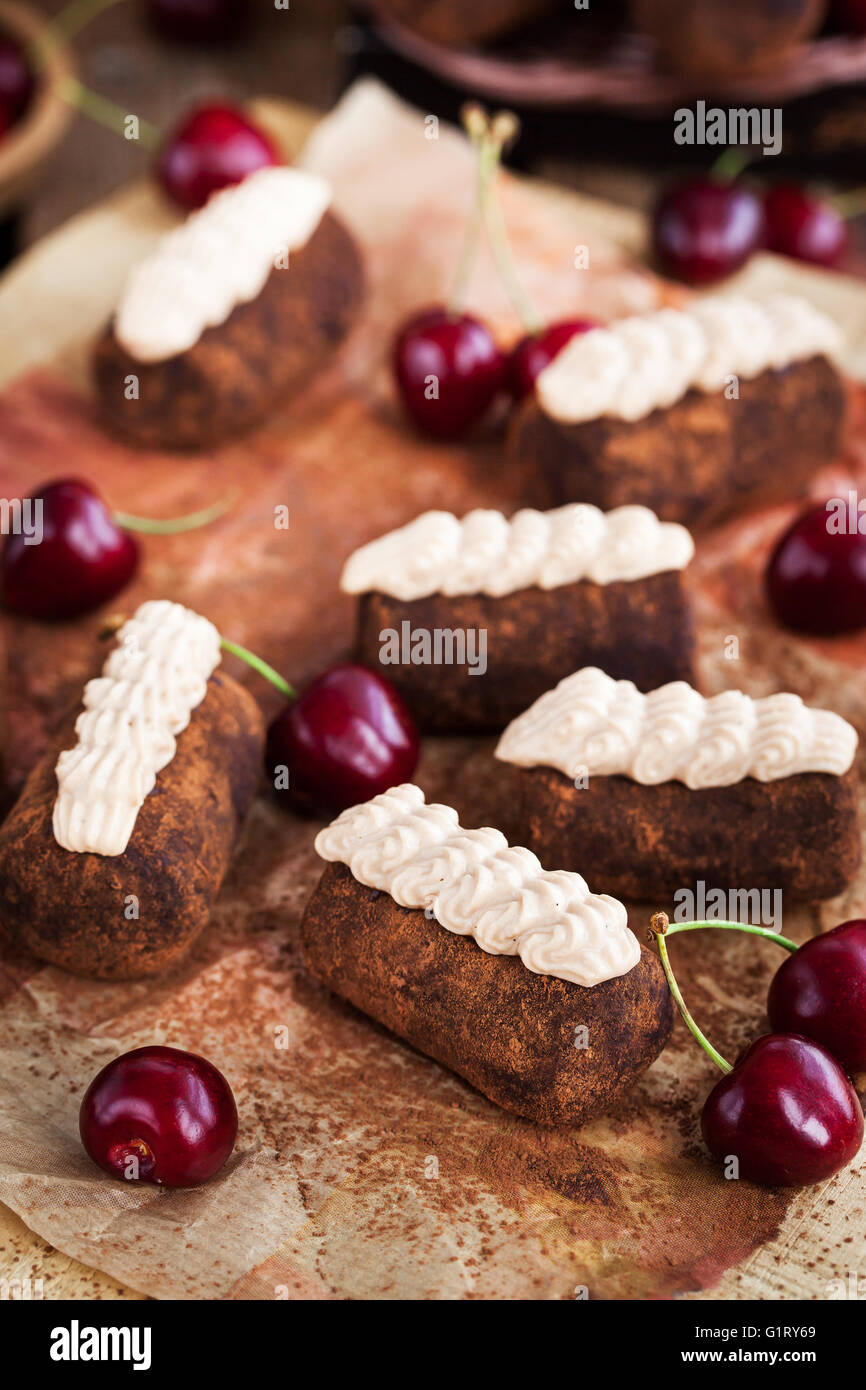 Chocolate rum balls cakes decorated with cream and fresh cherry Stock