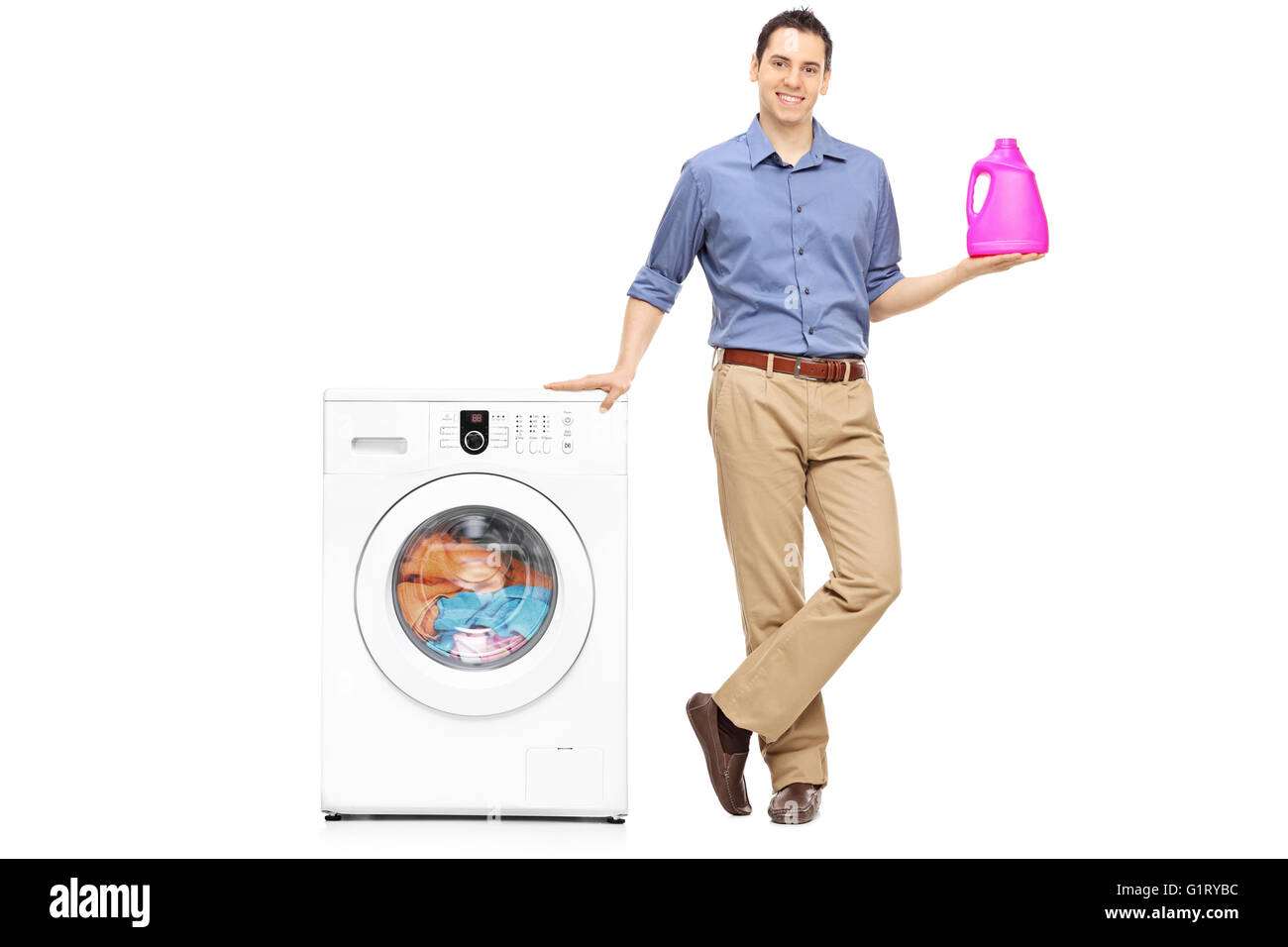 Young man holding a laundry detergent next to a washing machine isolated on white background Stock Photo