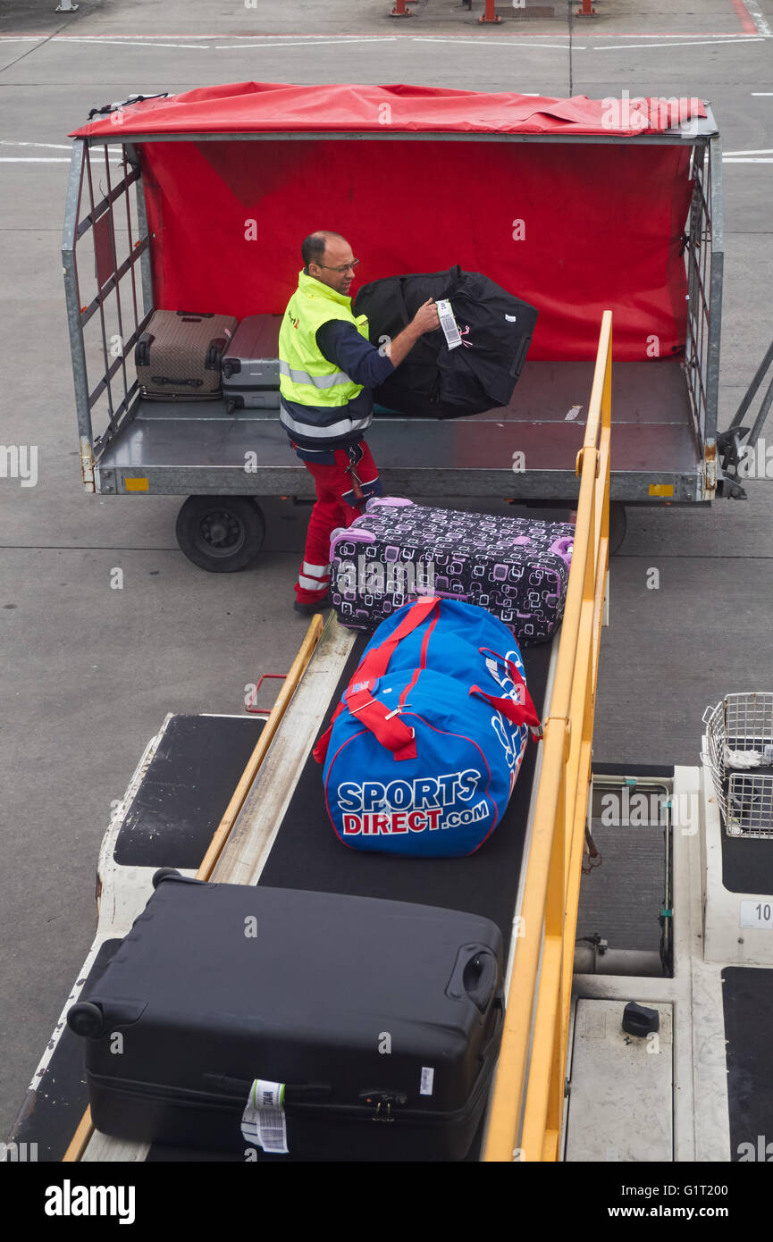 Airport worker loading baggage on aircraft at London Stansted Airport