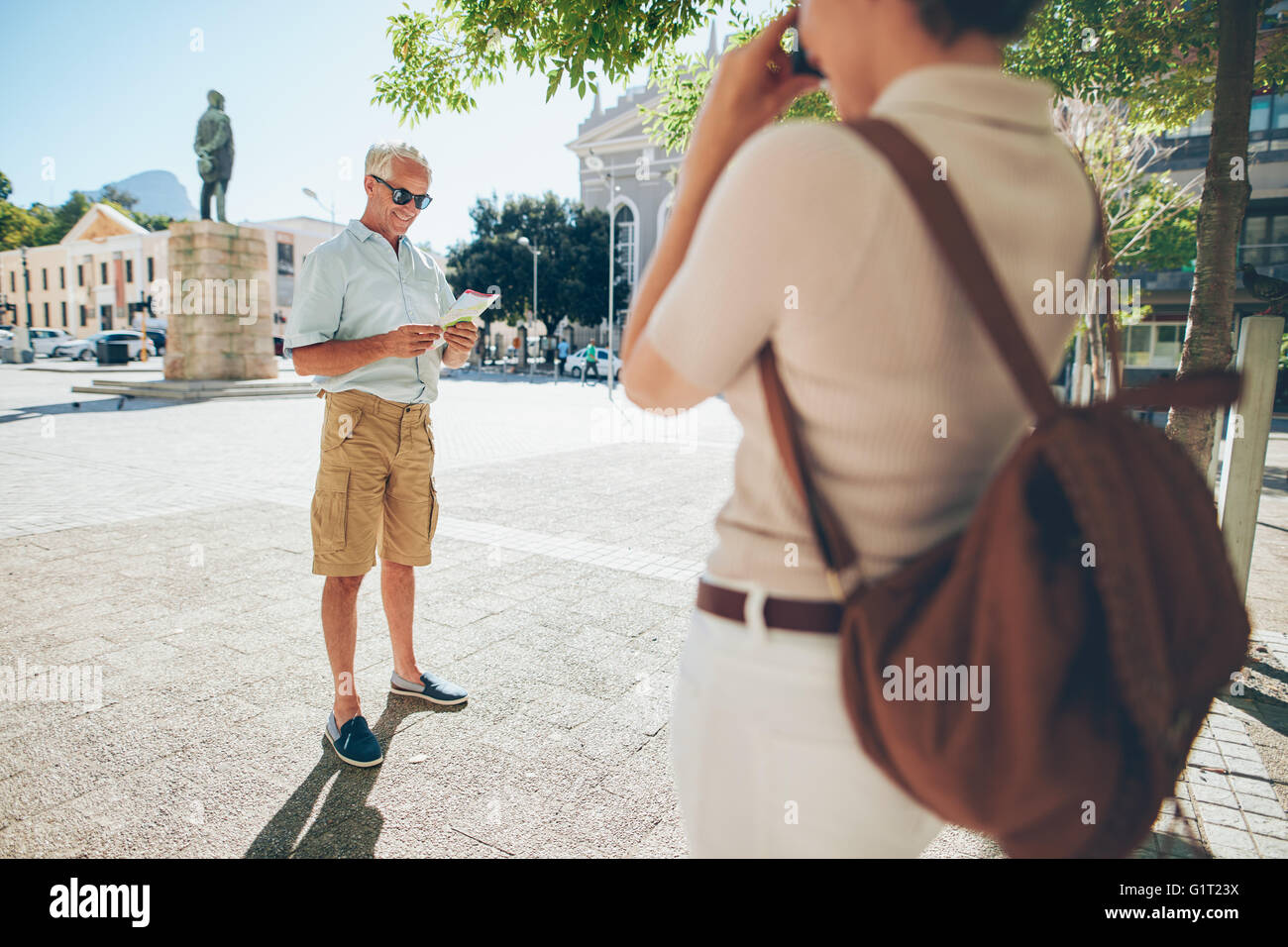 Senior man being photographer by a woman in the city during their vacation. Senior couple taking photos on their vacation. Stock Photo