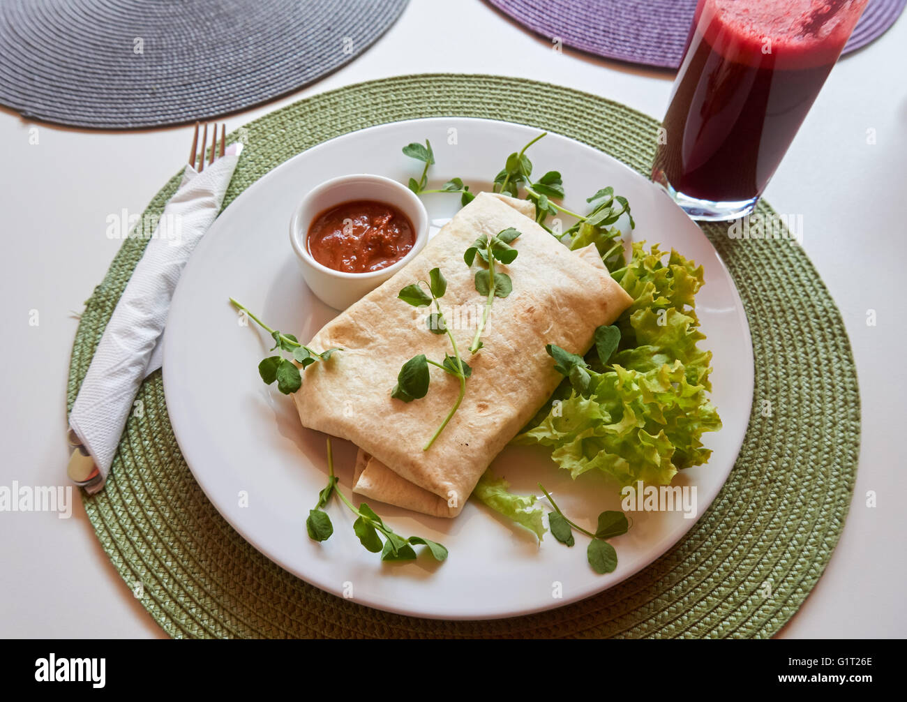Vegan burrito with tomato salsa, fresh lettuce and apple and beetroot juice Stock Photo