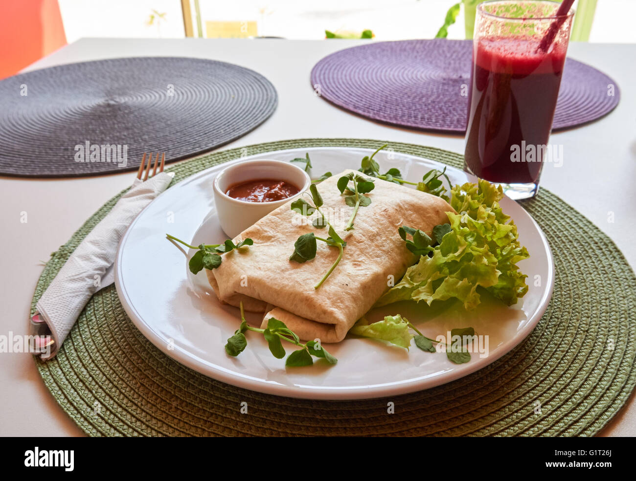 Vegan burrito with tomato salsa, fresh lettuce and apple and beetroot juice Stock Photo