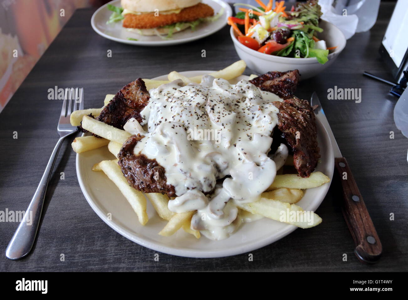 A Plate Of Steak With Mushroom Sauce And Chips With A Bowl Of Greek Stock Photo Alamy