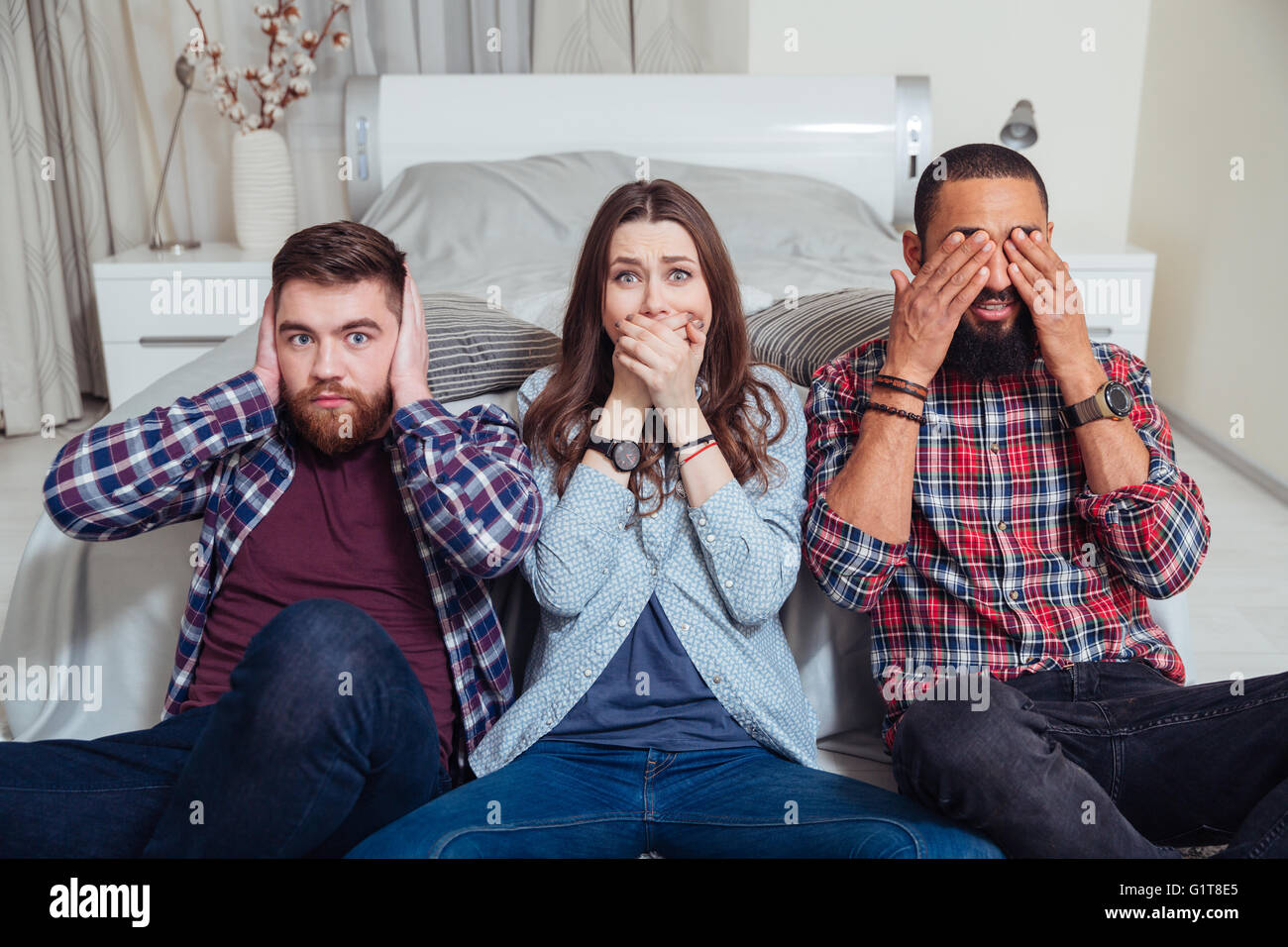 Three young friends sitting in see so evil, hear no evil, speak no evil  poses at home Stock Photo - Alamy