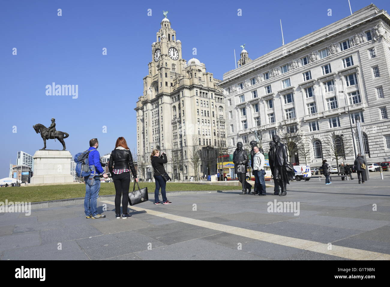 Beatles fans pose for photographs with statue at Pierhead, Liverpool, UK Stock Photo