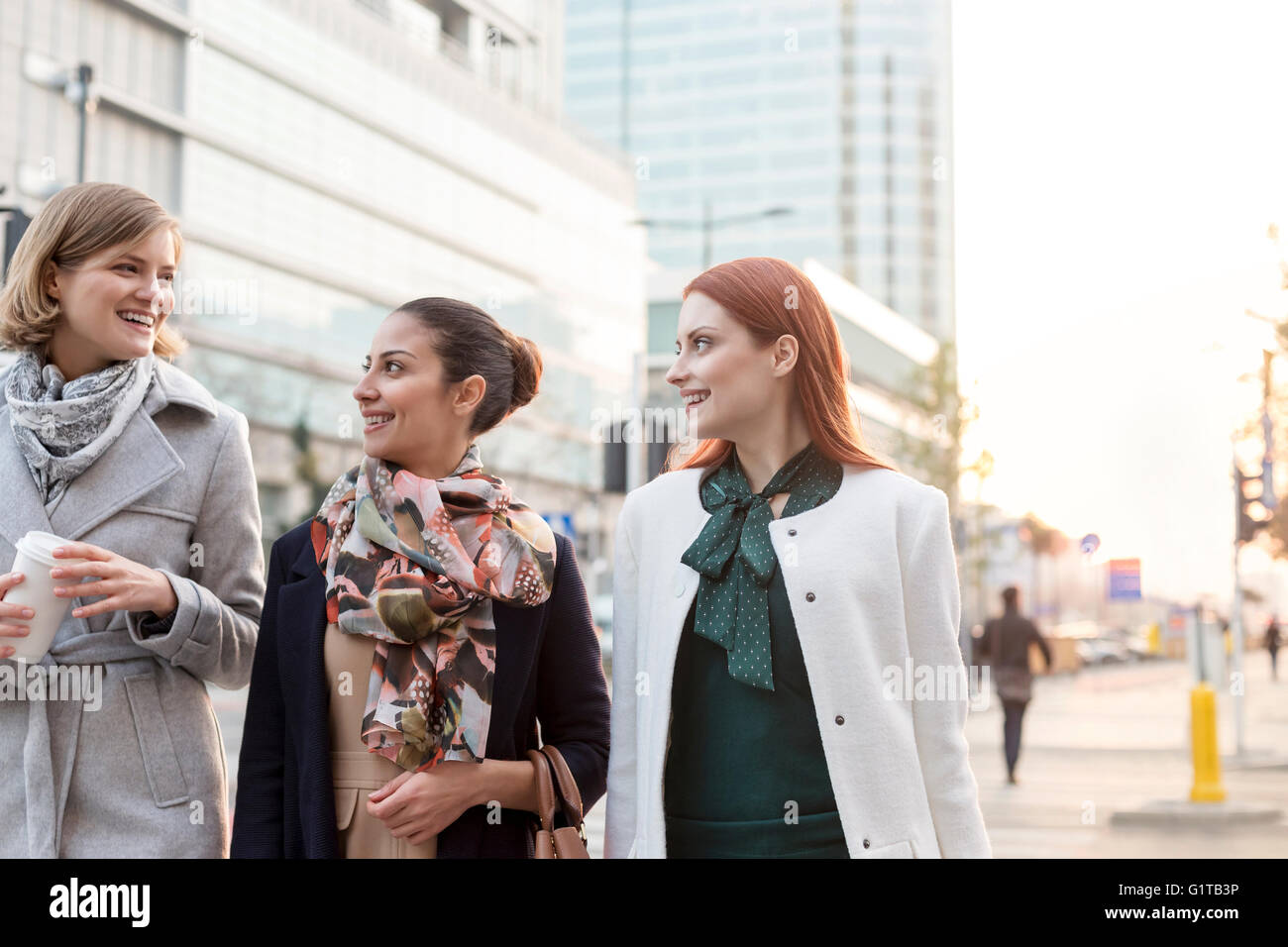 Businesswomen walking with coffee in city Stock Photo