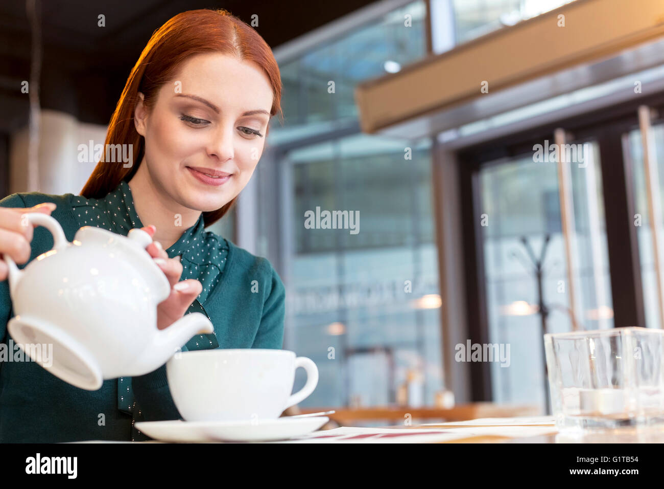 Smiling woman pouring tea in cafe Stock Photo