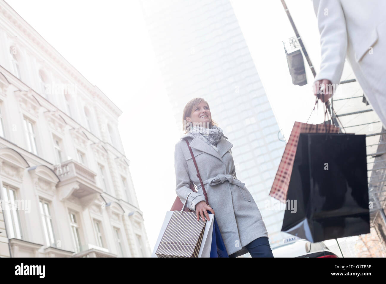 Women with shopping bags crossing city street below highrise Stock Photo