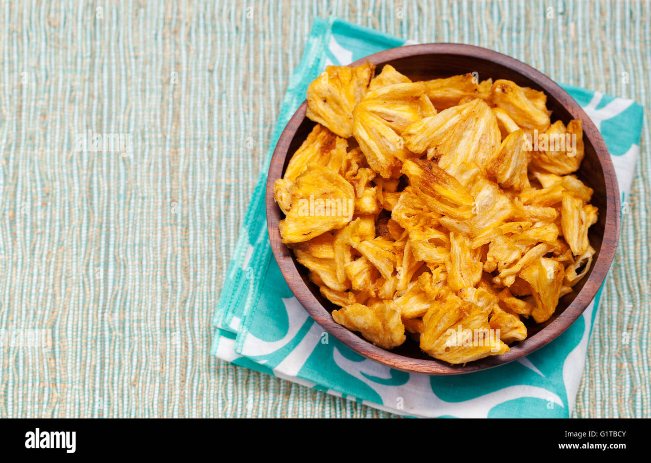 Dried dehydrated deep fried pineapple chips in a wooden bowl Stock