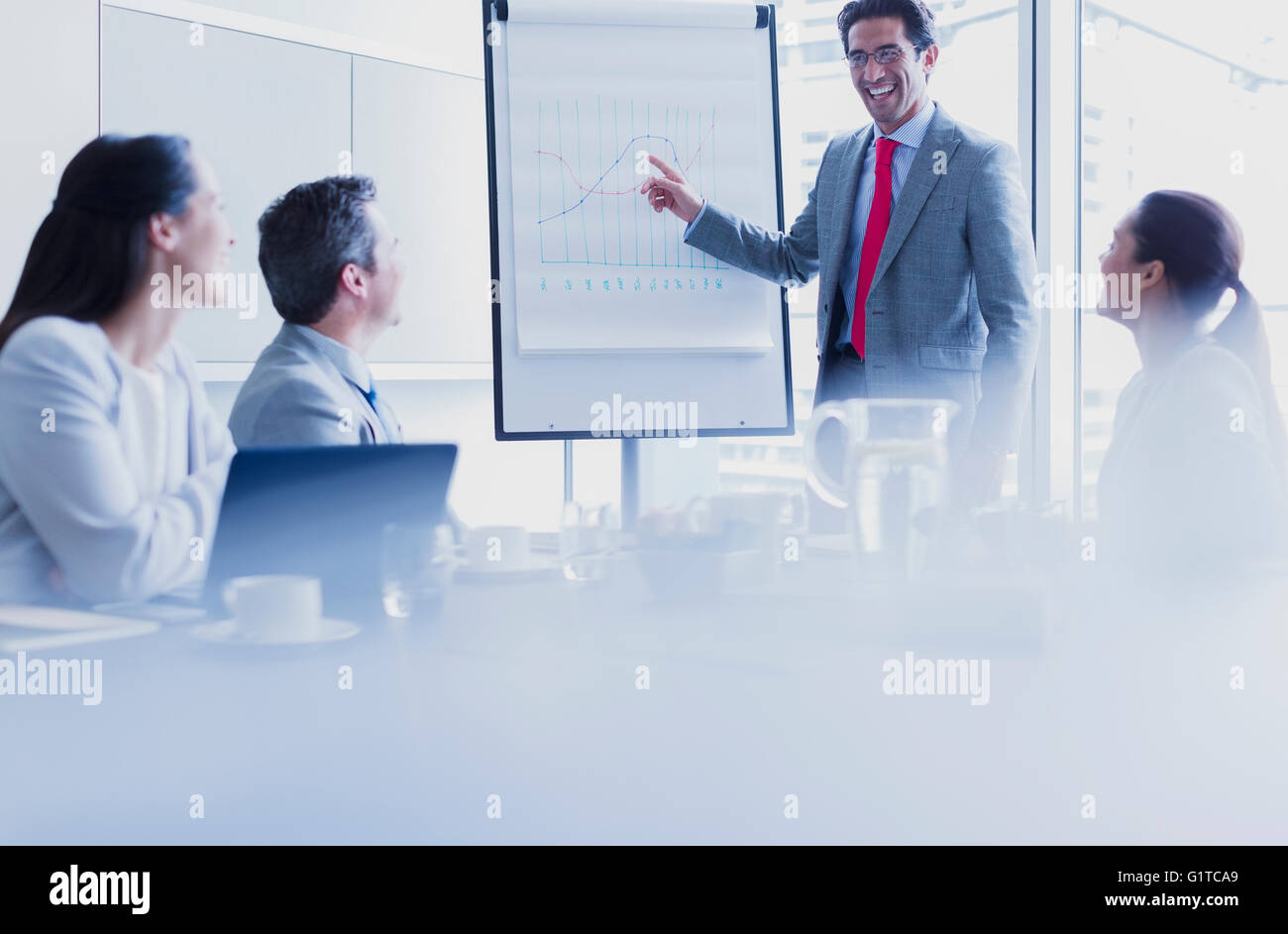 Smiling businessman leading meeting at flip chart in conference room Stock Photo