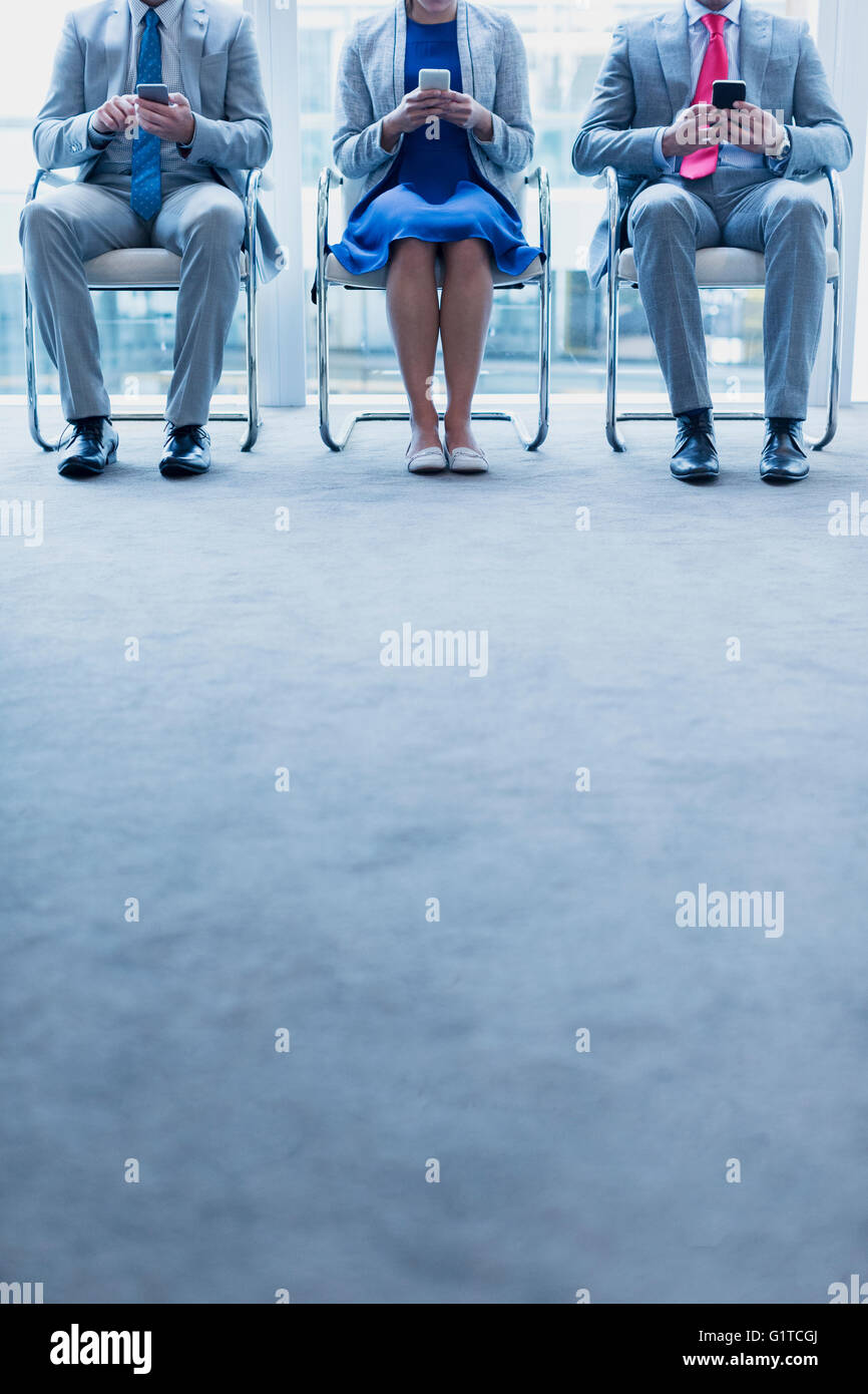 Business people with cell phones waiting in a row Stock Photo