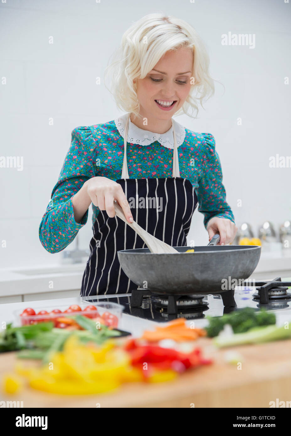 Smiling woman in apron cooking in kitchen Stock Photo