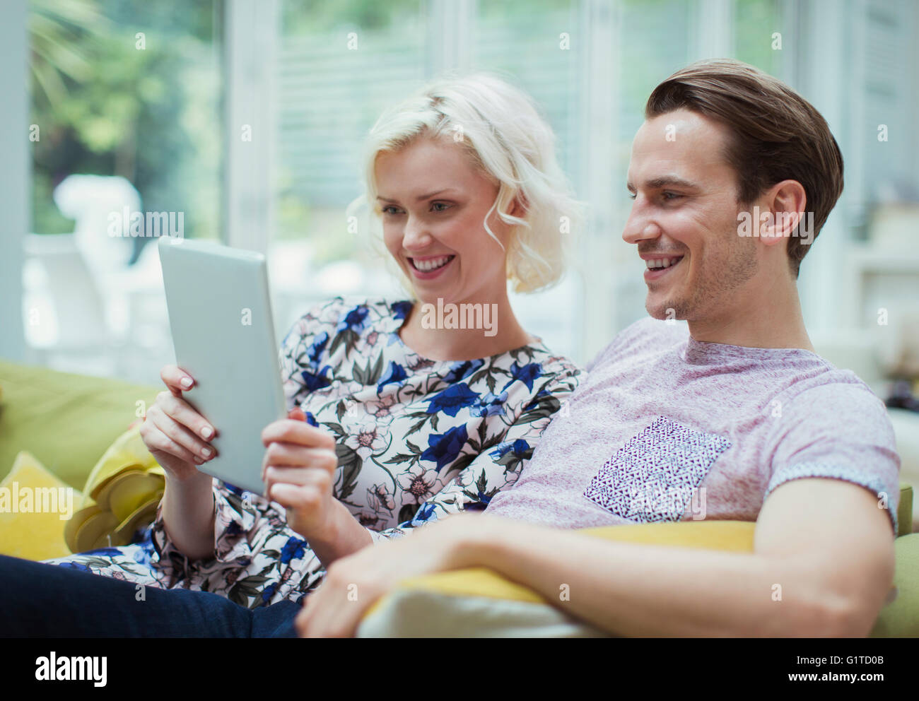 Couple using digital tablet on living room sofa Stock Photo