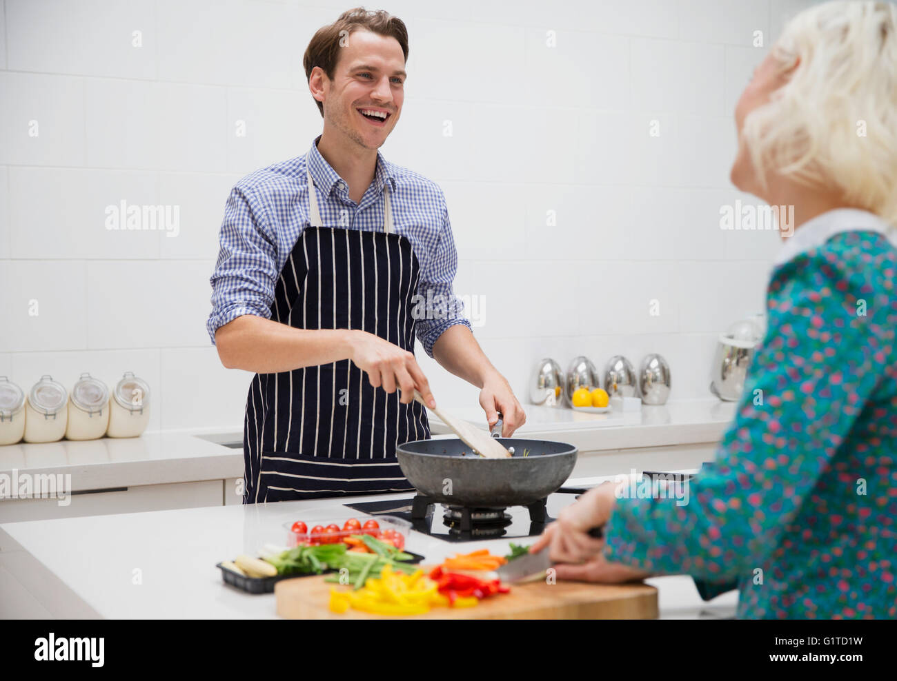 Smiling couple cutting and cooking vegetables in kitchen Stock Photo