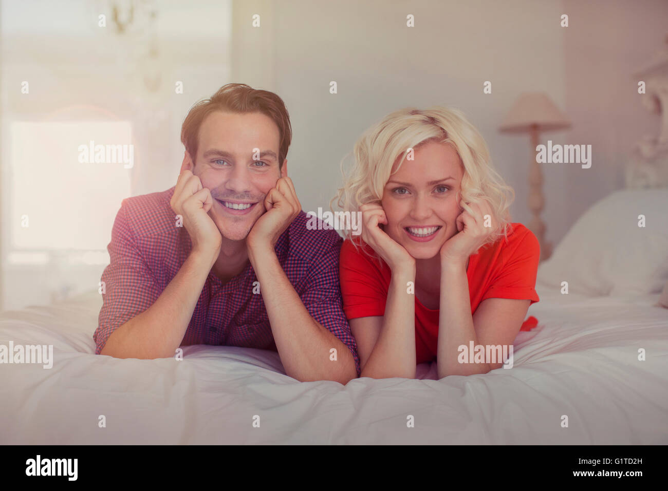 Portrait smiling couple with head in hands on bed Stock Photo