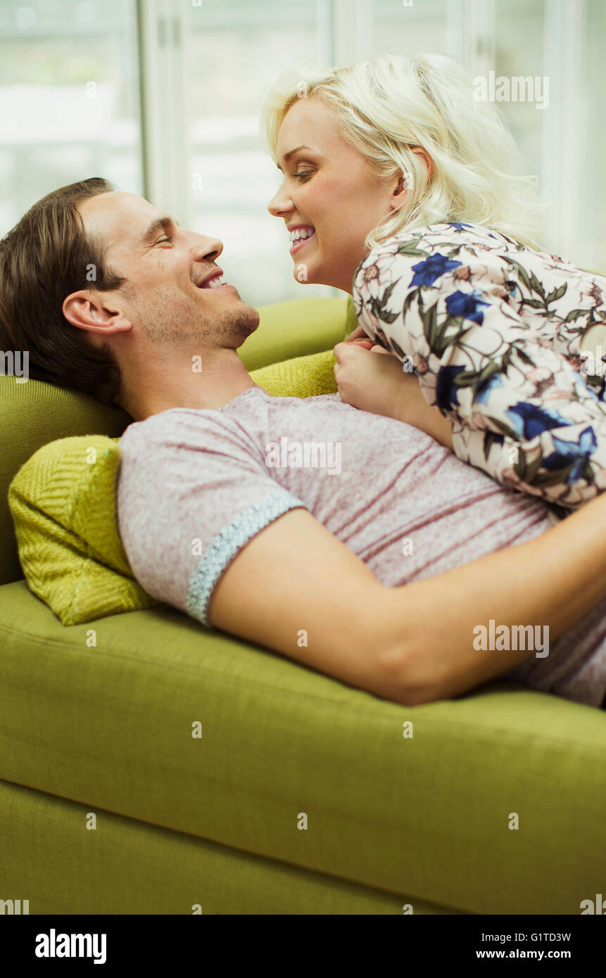 Affectionate couple laying on living room sofa face to face Stock Photo
