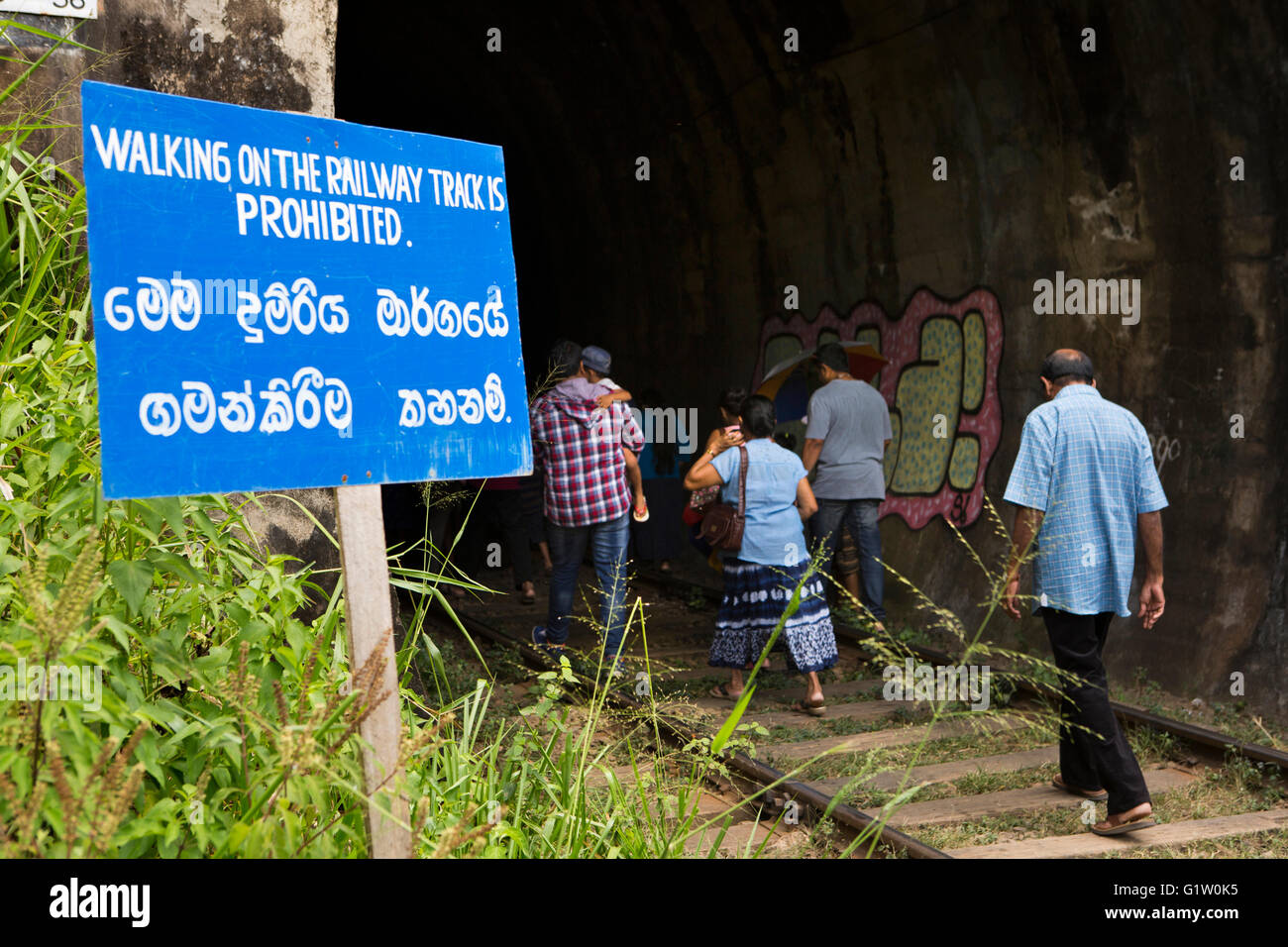 Sri Lanka, Ella, Demodara,  people ignoring safety sign, walking through tunnel Stock Photo