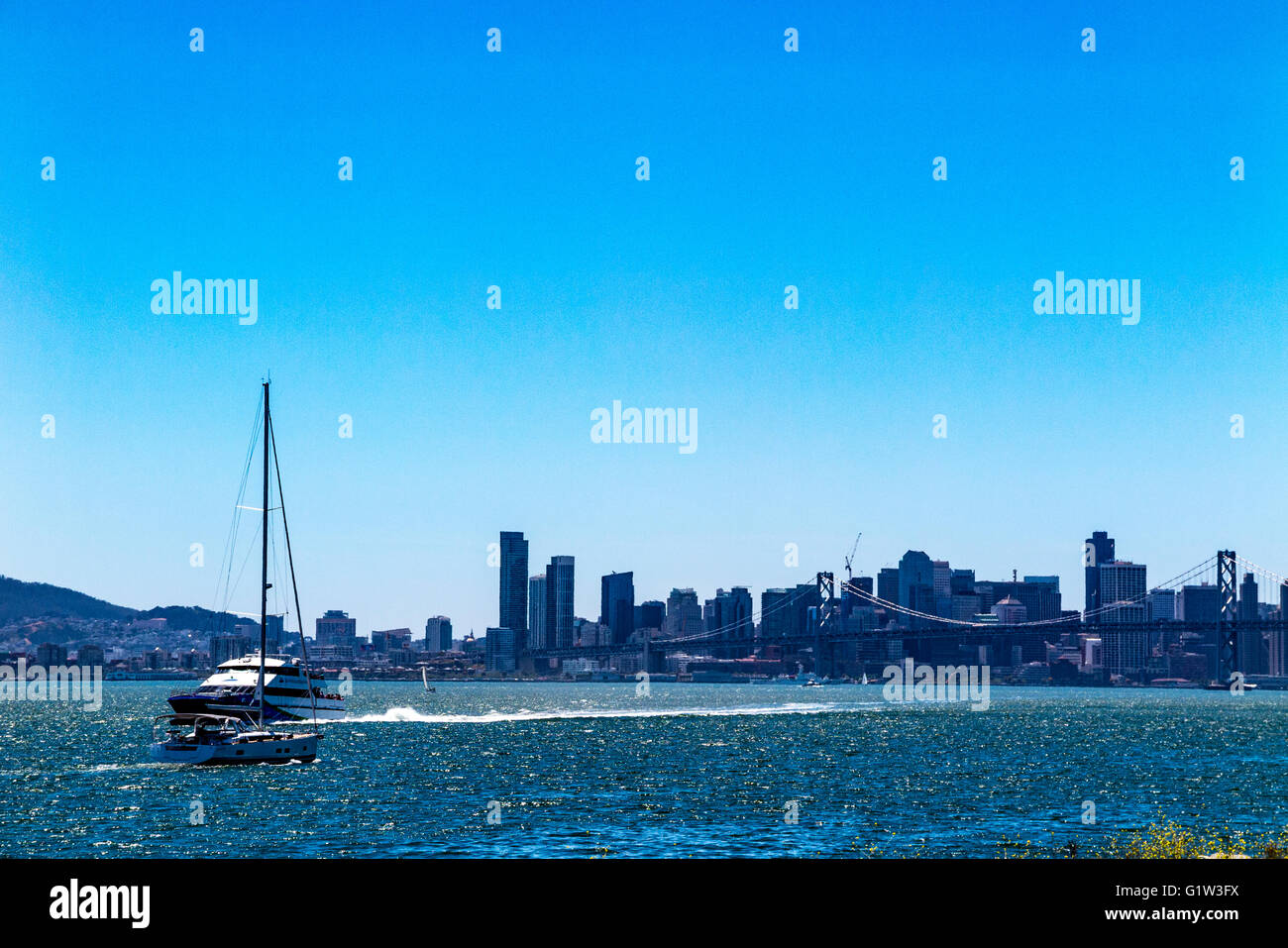 A Ferry boat arriving to the Port of Oakland with the San Francisco Skyline and the Bay Bridge in the background Stock Photo
