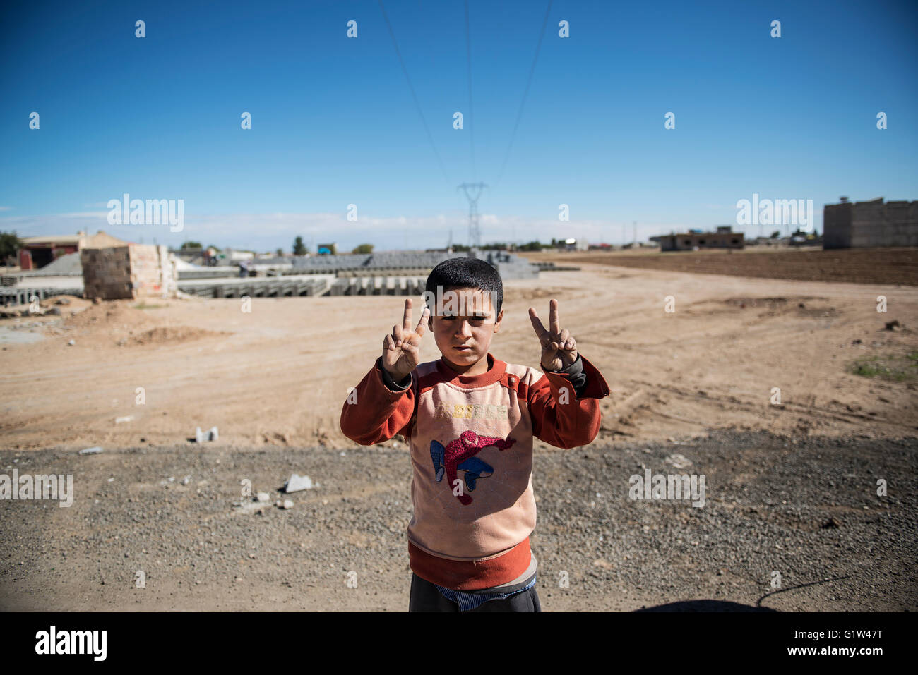 A Kurdish boy from Kobani does the victory sign as he poses for a photo, at the Turkish town of Suruc, near the Turkish-Syrian border. Thousands of Kurdish people were forced to abandon the Syrian town of Kobani, which is under siege by Islamic State forces. Most of them are living in refugee camps in the Turkish town of Suruc. Stock Photo
